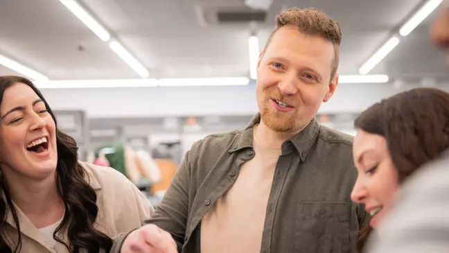 A munkatársak együtt nevetnek egy csapatmegbeszélésen az eladótérben