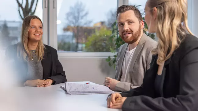 Munkatársak ülnek egy asztalnál, és beszélgetnek egymással